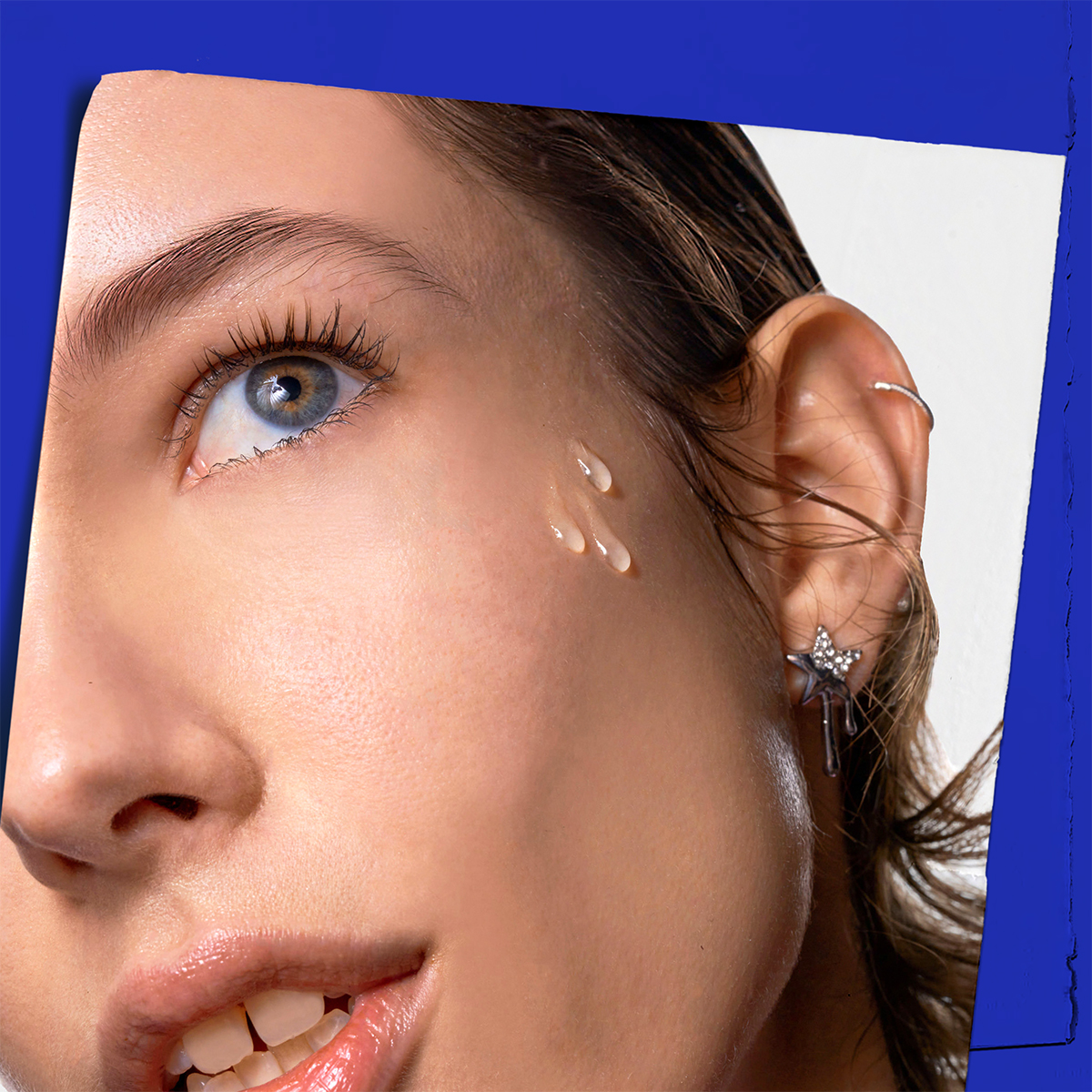 Primo piano dell'applicazione: gocce di siero Midnight Recovery Concentrate sulla pelle luminosa del viso.