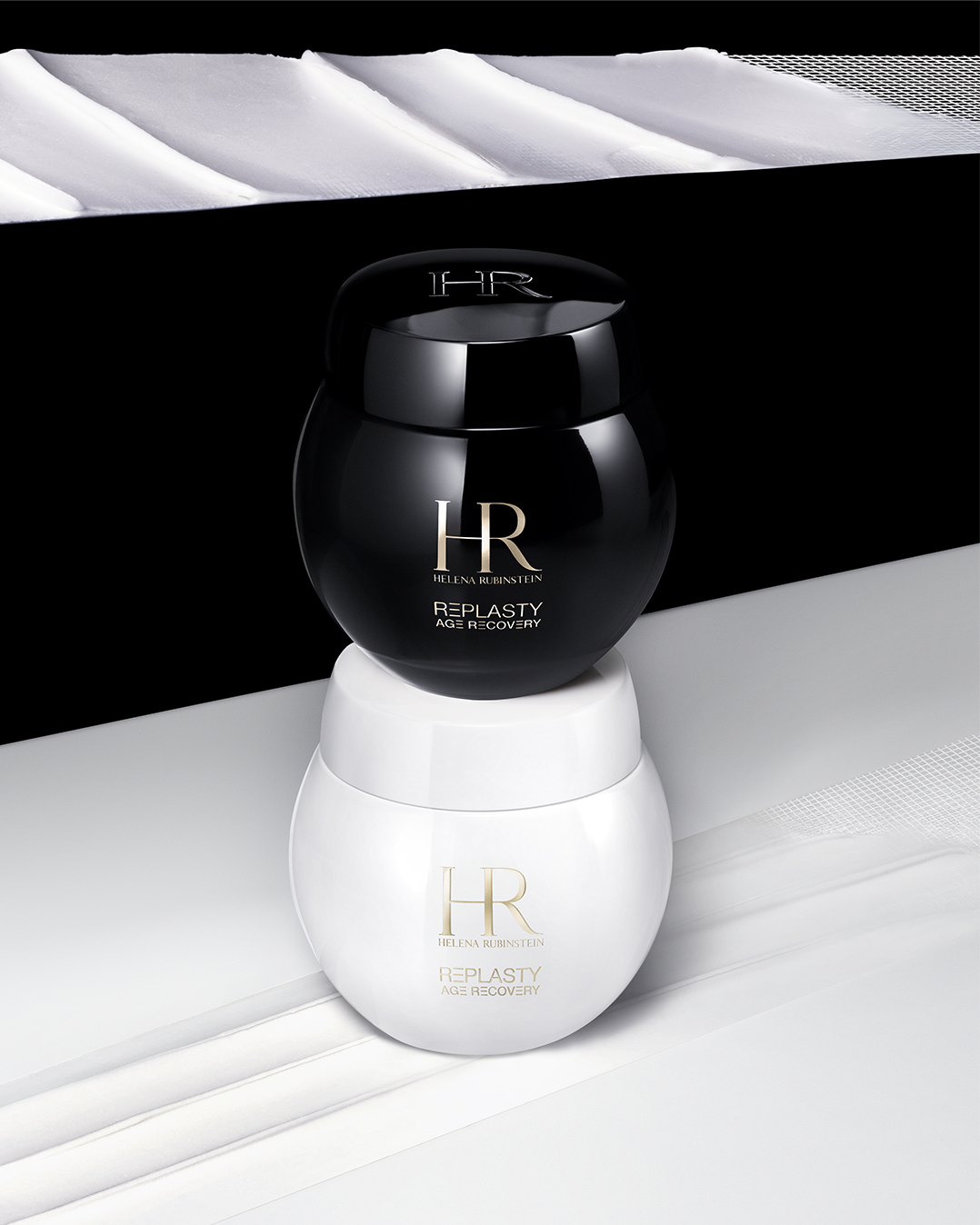 Duo di creme Helena Rubinstein Replasty Age Recovery, con il vasetto nero da notte sovrapposto al vasetto bianco da giorno.