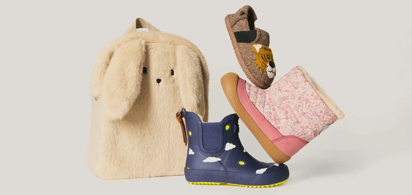 Zaino con coniglio di peluche, stivali da pioggia blu con motivi di sole e nuvole, stivali invernali rosa con fiori e pantofole marroni pelose con faccia di tigre.