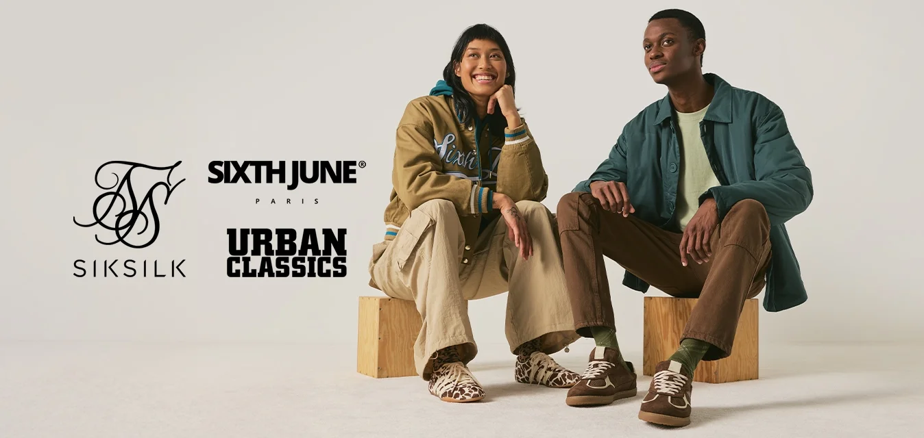 Due giovani seduti su blocchi di legno, vestiti in modo casual, sembrano rilassati su uno sfondo chiaro e uniforme.