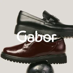 Mocassino in pelle nera impilato sopra una scarpa oxford marrone scuro lucida, entrambe bilanciate su una sfera di marmo nero contro uno sfondo semplice.