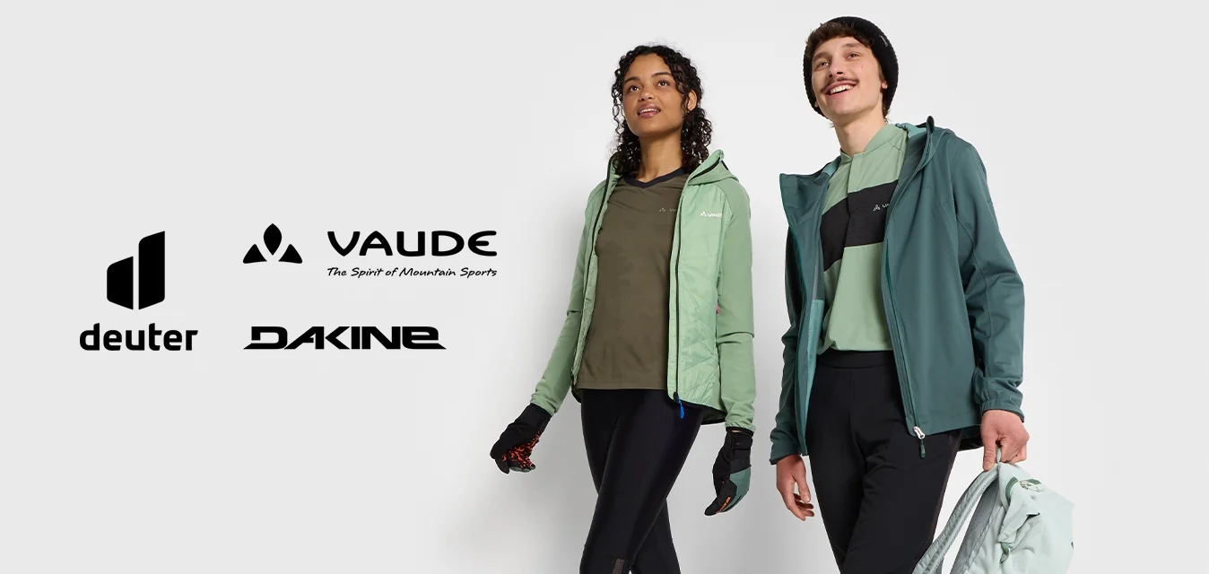 Due persone camminano su una superficie liscia, indossando giacche leggere in verdi e neri tenui, abbinate a leggings neri e scarpe sportive.