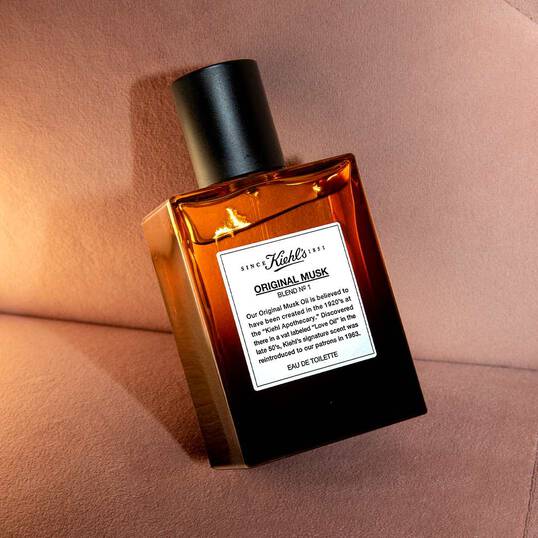Flacone ambrato di Kiehl&rsquo;s Original Musk Eau de Toilette su sfondo beige, illuminazione laterale.