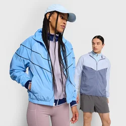 Due persone indossano giacche leggere in tonalità blu e grigie, abbinate a pantaloni corti rosa. Le giacche presentano pannelli e cerniere a contrasto.