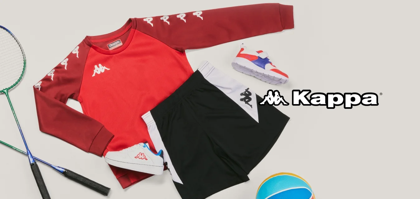 Maglia sportiva rossa a maniche lunghe, pantaloncini neri e bianchi, due scarpe da ginnastica, due racchette da badminton e una palla da basket colorata su uno sfondo chiaro.