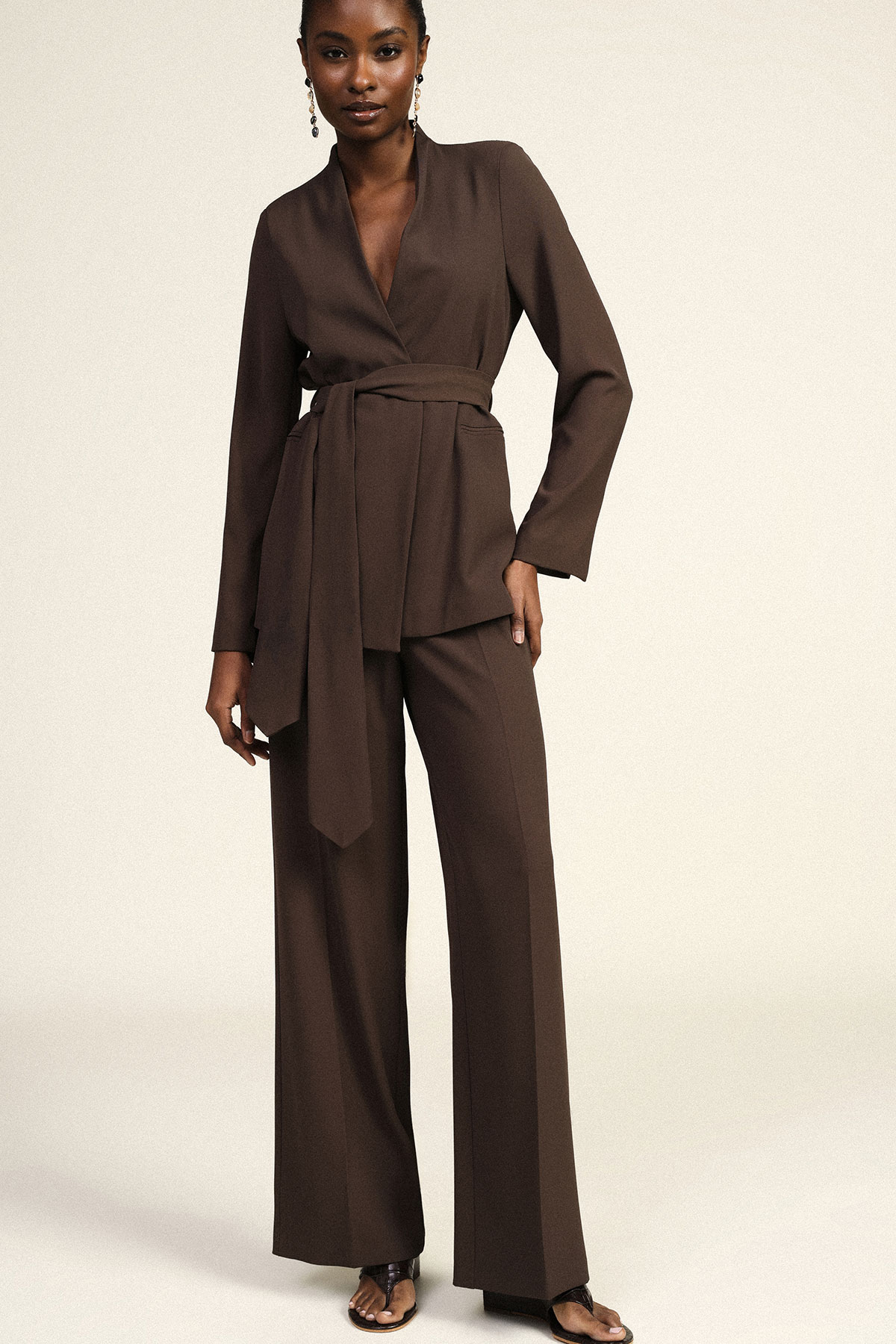Model modelling brown belted wrap blazer and wide-leg trousers, full-length women's outfit on a neutral background