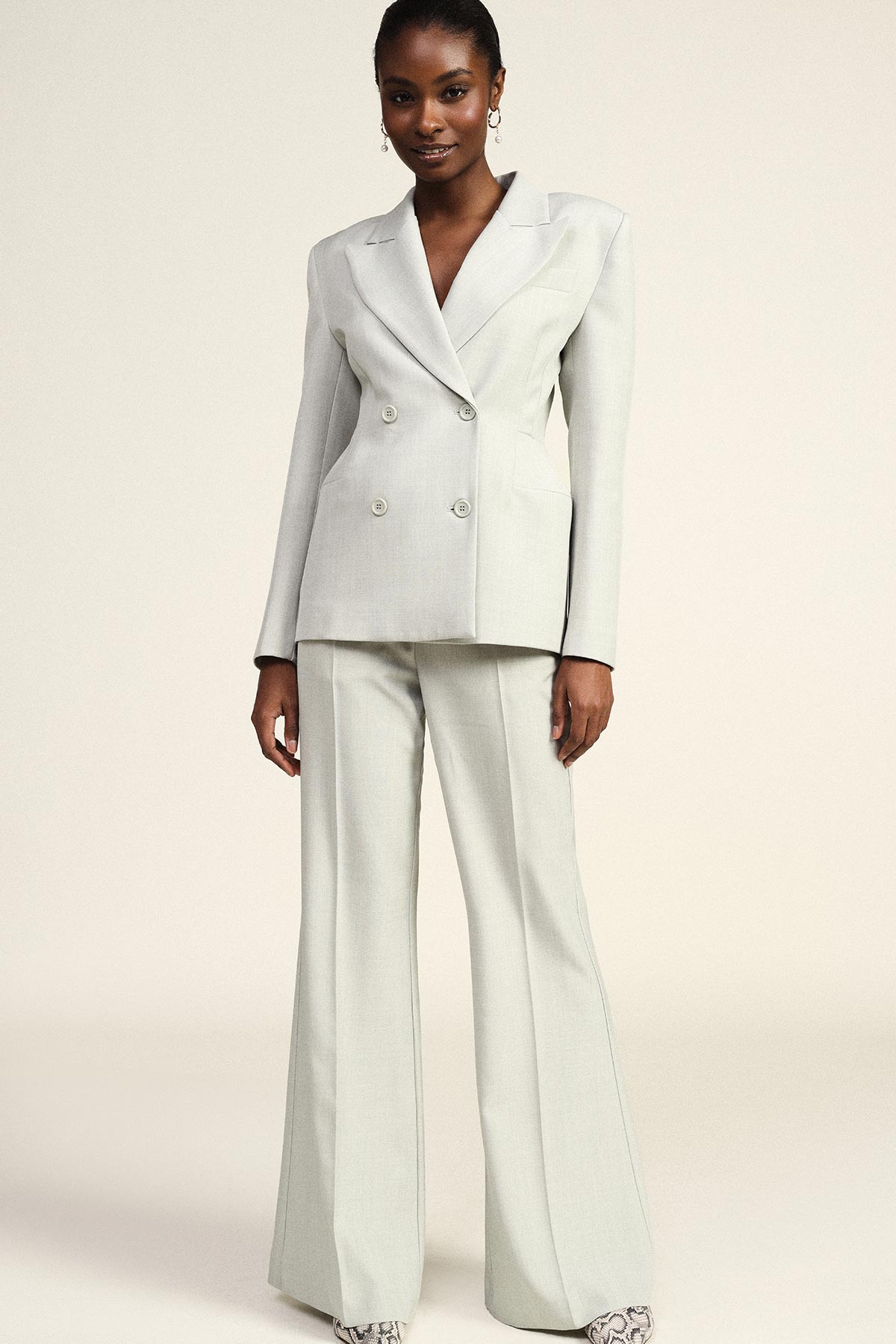 Model wearing pale grey double-breasted blazer with matching wide-leg trousers on a neutral background