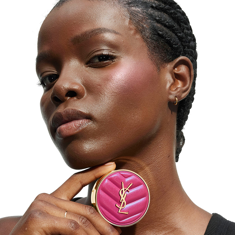 Una modella dalla pelle scintillante con un compatto YSL rosa vivace.