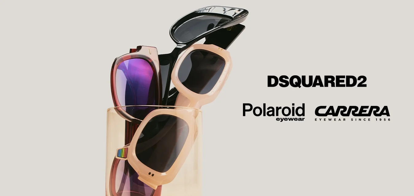 Tre paia di occhiali da sole con diversi stili di montatura in un contenitore di vetro trasparente color ambra su uno sfondo beige semplice.