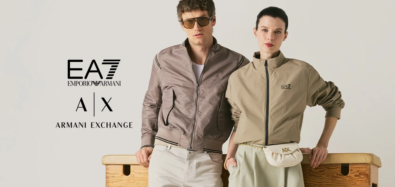 Uomo e donna si appoggiano a una cassa da ginnastica in legno, entrambi indossano abiti casual in tonalità neutre, in uno spazio minimalista e luminoso.