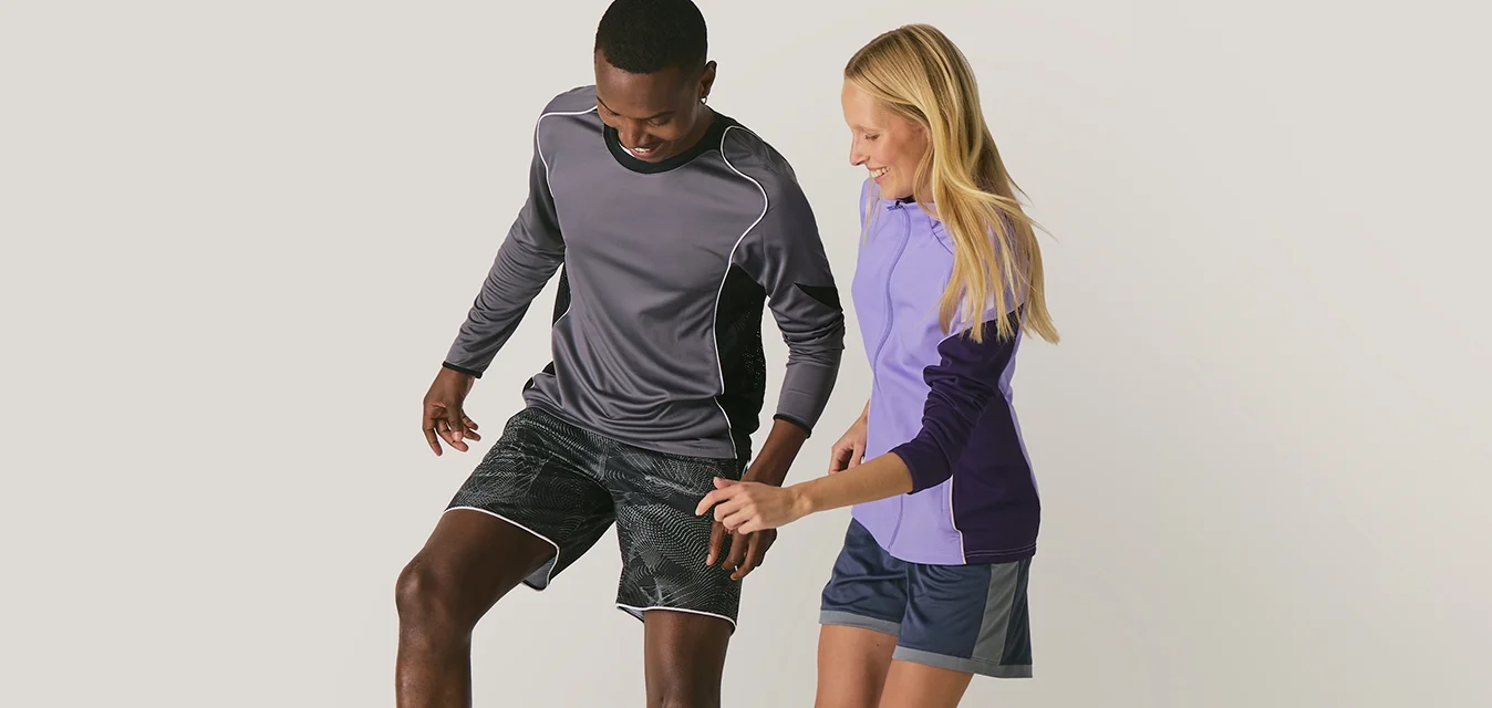 Due persone in abbigliamento sportivo che giocano a calcio, una controlla la palla con il piede mentre l'altra cerca di prenderla.