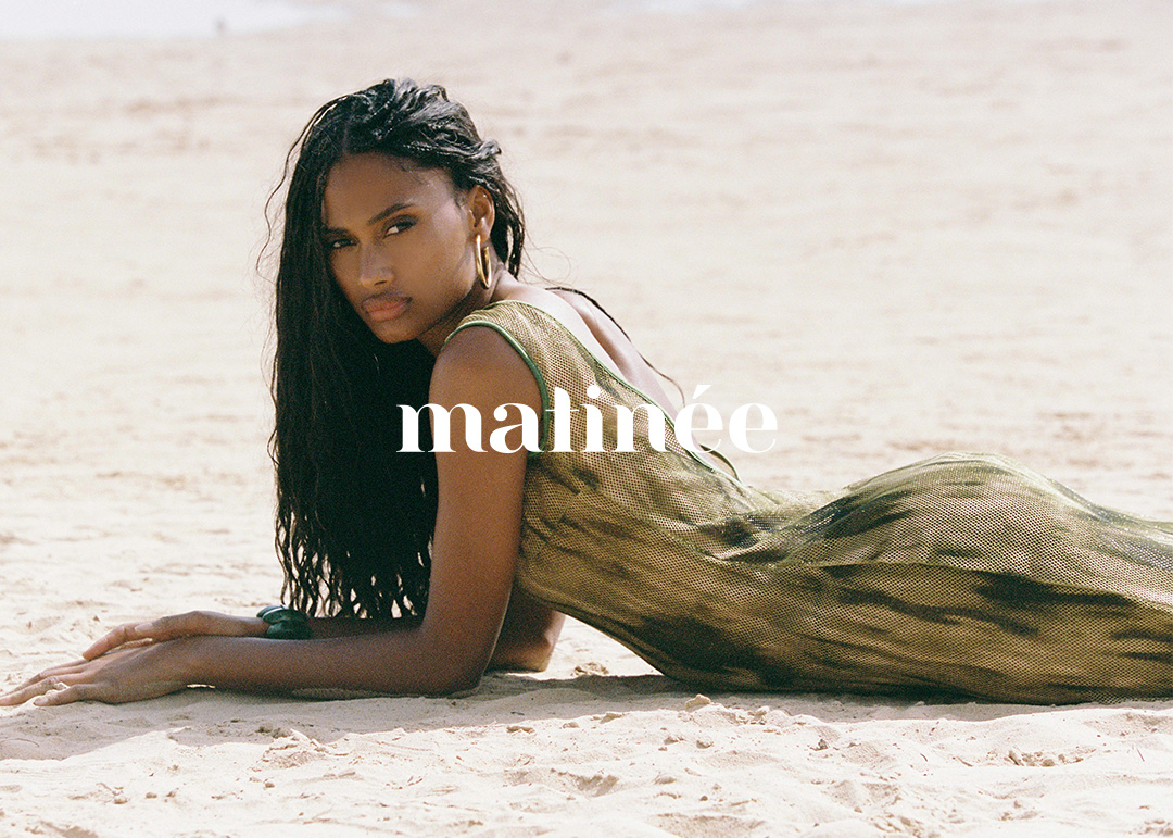 Woman with long dark hair lying on a sandy beach wearing a green summer dress, editorial 'matinée' logo overlaid