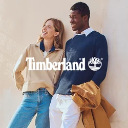 Maglione beige con zip, colletto blu; maglione blu navy a coste; jeans azzurri; scarpe marroni; pantaloni bianchi; giacca marrone; parete testurizzata; persiane verdi.