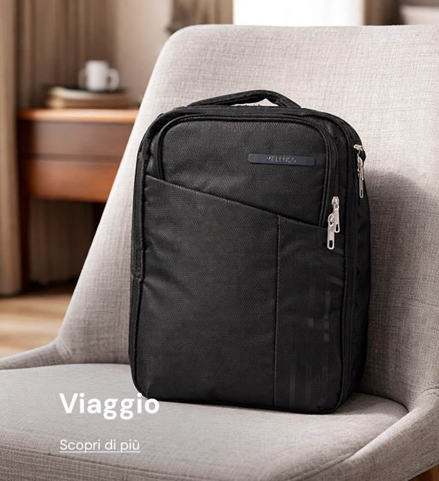 Black compact travel backpack with multiple zippered compartments on a beige chair in a cozy hotel-style room