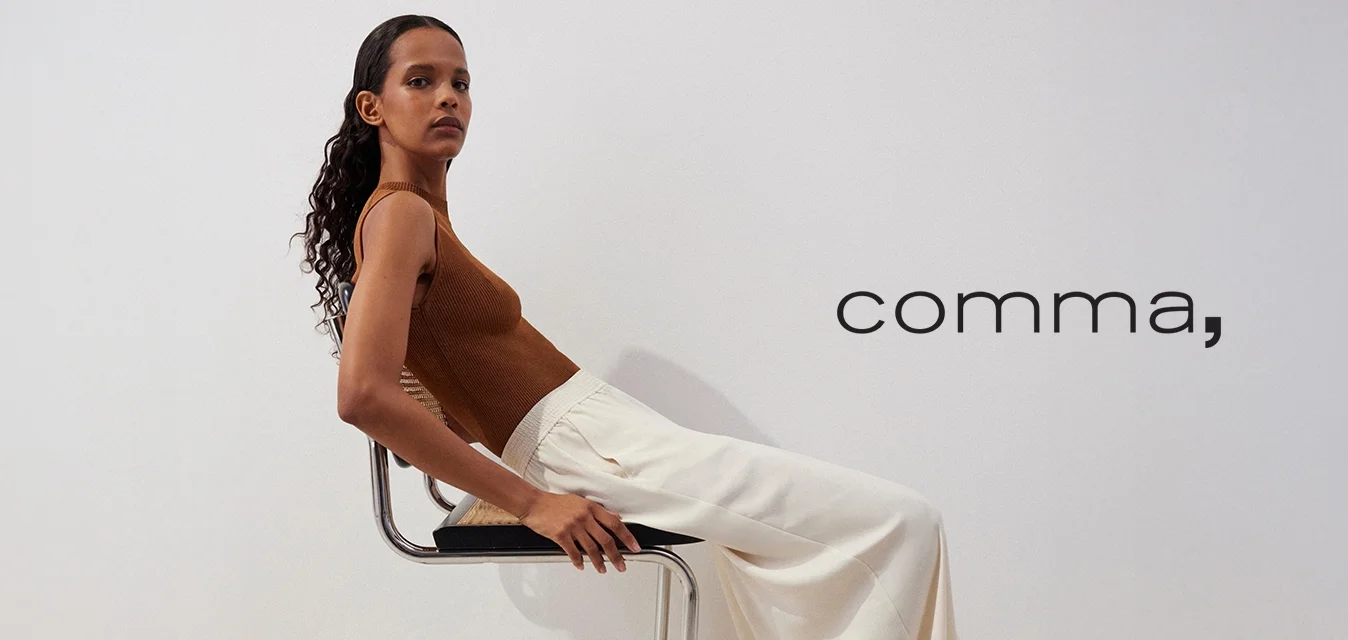 Top senza maniche marrone a coste abbinato a pantaloni bianchi a gamba larga e fluida, seduto su una sedia metallica con sedile nero, texture liscia e sfondo chiaro.