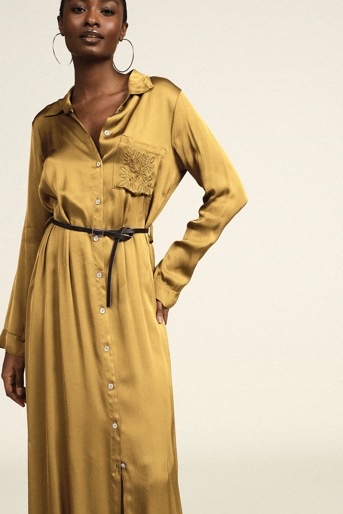 Four female models showcasing fashion: mustard belted shirt dress, beige slip dress, copper satin draped gown, light‑grey double‑breasted blazer dress