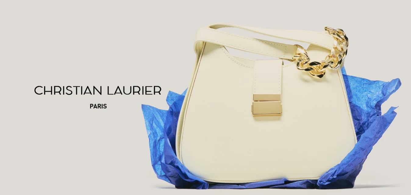 Borsa a mano in pelle crema con dettaglio a catena d'oro, poggiata su carta velina blu spiegazzata su uno sfondo neutro.