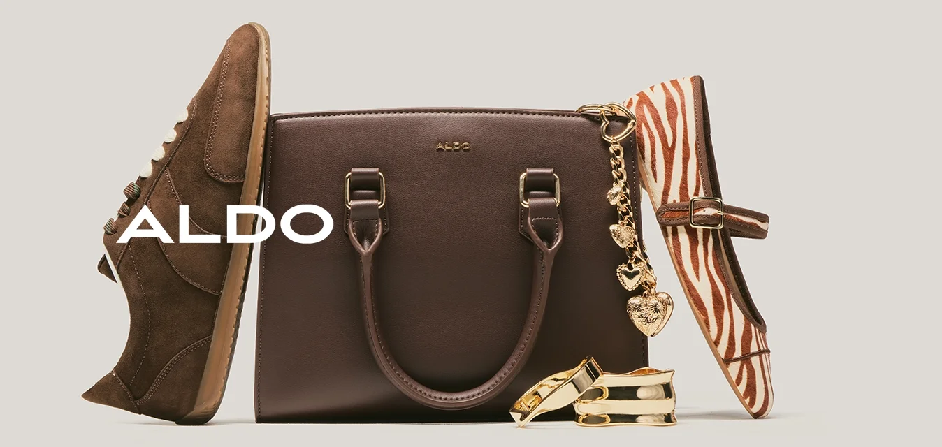 Borsa a mano in pelle marrone con ciondolo a forma di cuore dorato, sneaker in camoscio marrone, scarpa piatta con stampa zebra e due braccialetti dorati su sfondo chiaro.