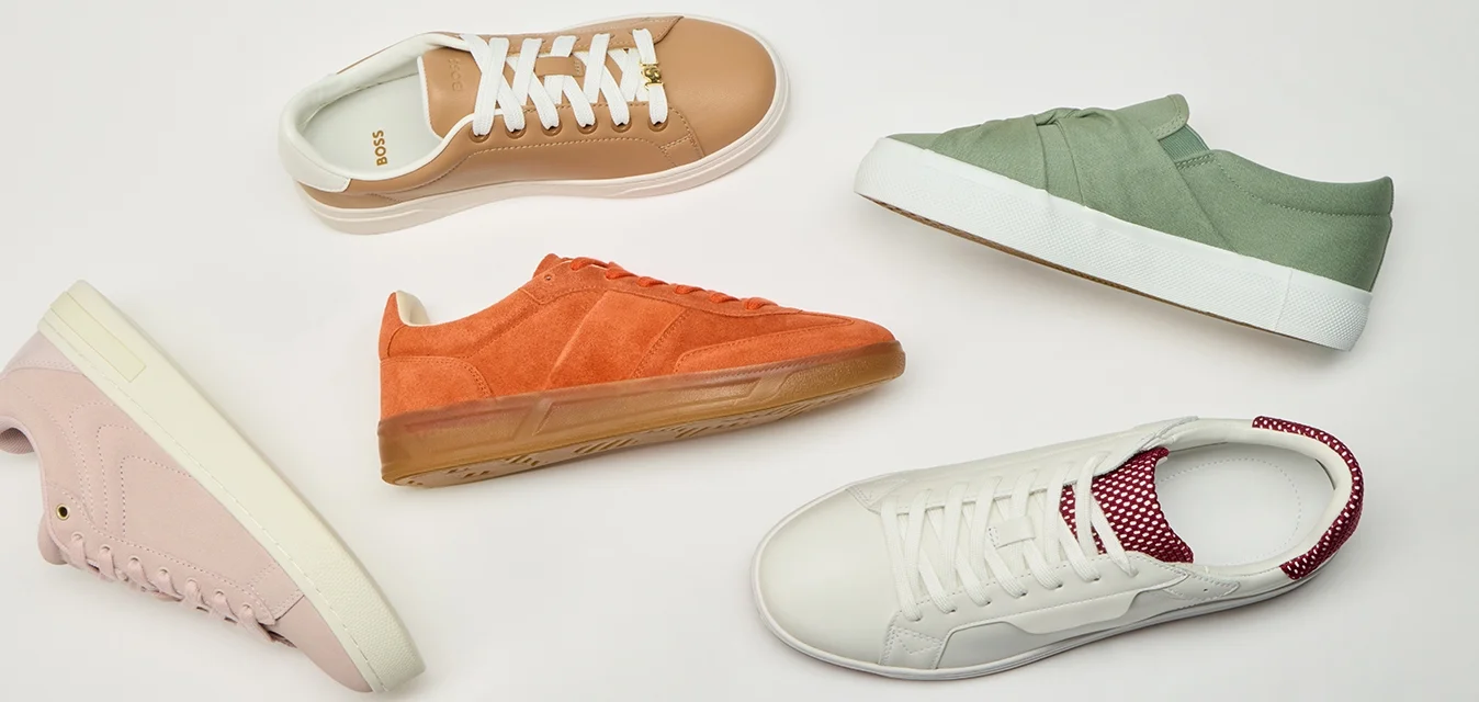 Sneaker casual variopinte in beige, arancione, verde, bianco con accenti rossi, rosa e blu disposte in cerchio su uno sfondo bianco.