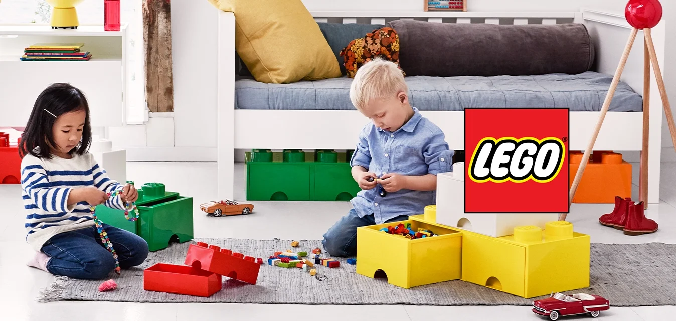 Due bambini seduti per terra giocano con grandi mattoncini colorati in una luminosa e moderna sala giochi.