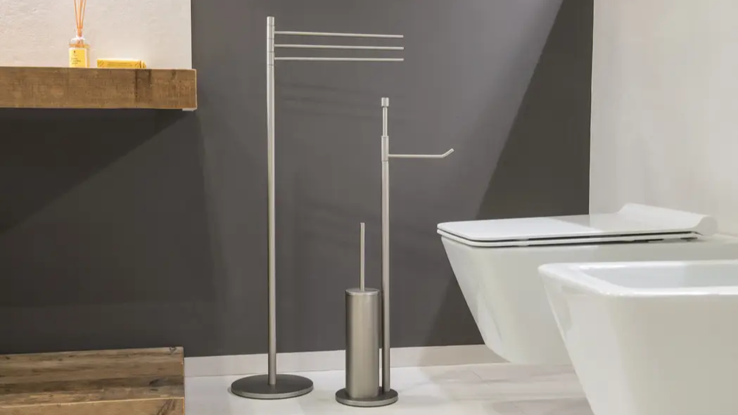 Modern bathroom with stainless-steel freestanding towel and toilet-roll stand, toilet brush, and wall-hung white toilet and bidet