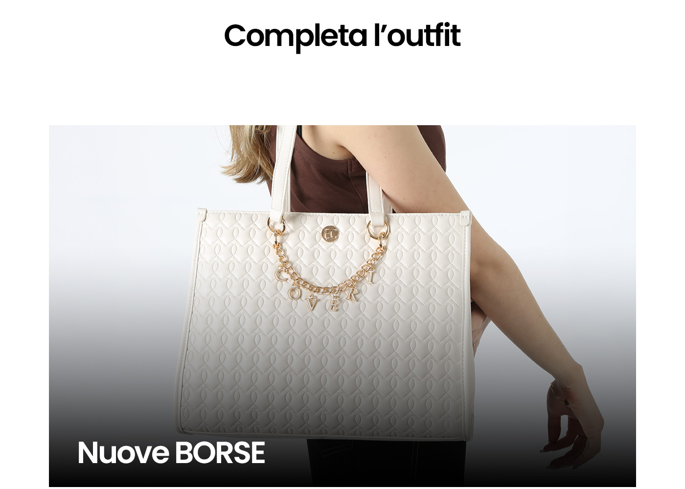 Woman carrying large white quilted tote bag with gold 'LOVE' charm chain and heart pattern, styled with sleeveless brown top