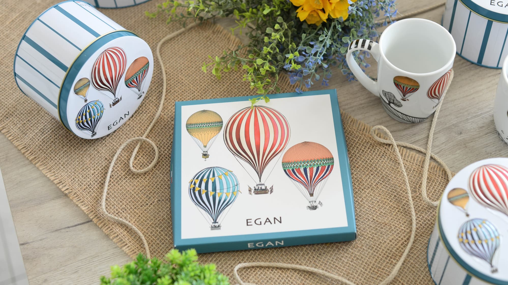 A ceramic cat in a top hat holds a bouquet of spring flowers in a whimsical garden.