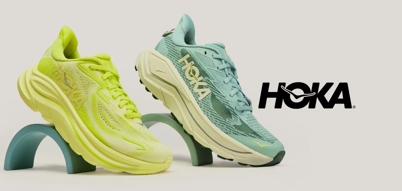 Due scarpe da corsa sportive, una giallo neon e una turchese, esposte su supporti curvi contro uno sfondo chiaro e uniforme.