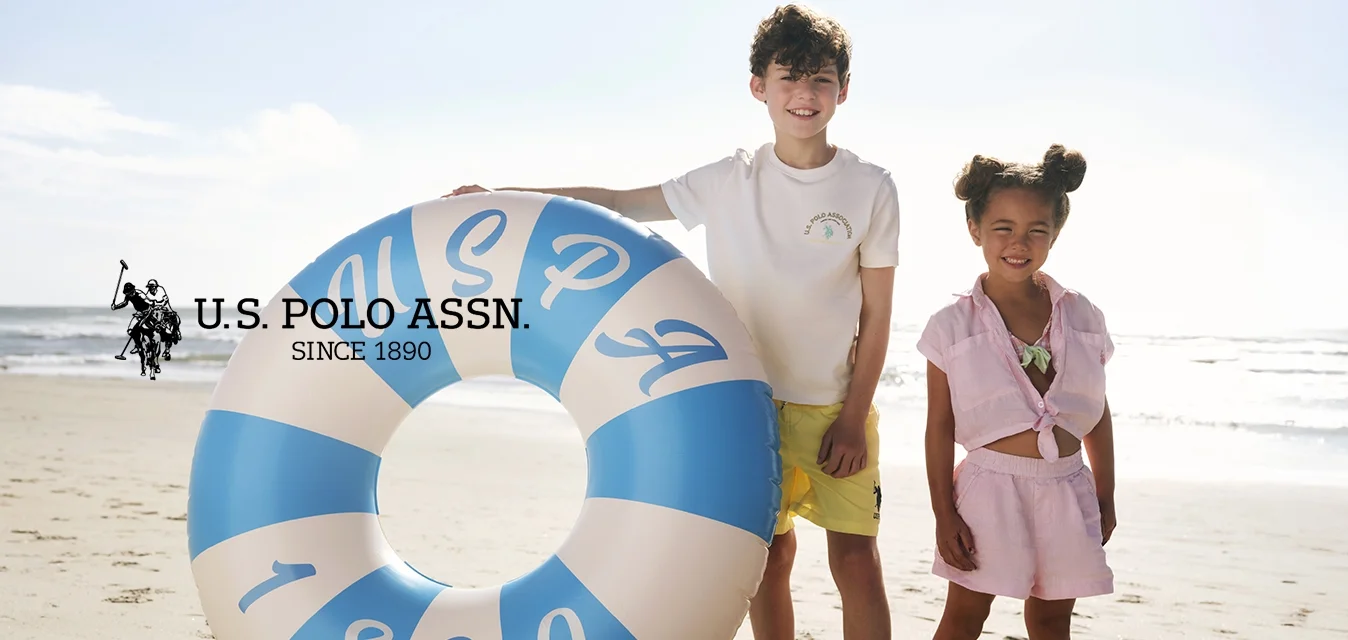 Due bambini in piedi a piedi nudi su una spiaggia sabbiosa, uno tiene un grande anello gonfiabile da nuoto blu e bianco con la scritta 