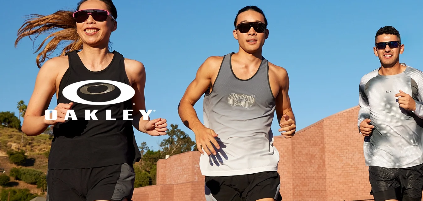 Quattro corridori in abbigliamento sportivo su una pista. Due indossano top neri e grigi, uno ha una maglietta a maniche lunghe argentata e l'altro indossa leggings blu navy e un top corto.