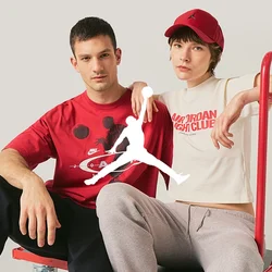 Due giovani adulti sono seduti su un carrello rosso a piattaforma; uno indossa una maglietta rossa con disegni, l'altro una maglietta bianca corta e un cappellino rosso.