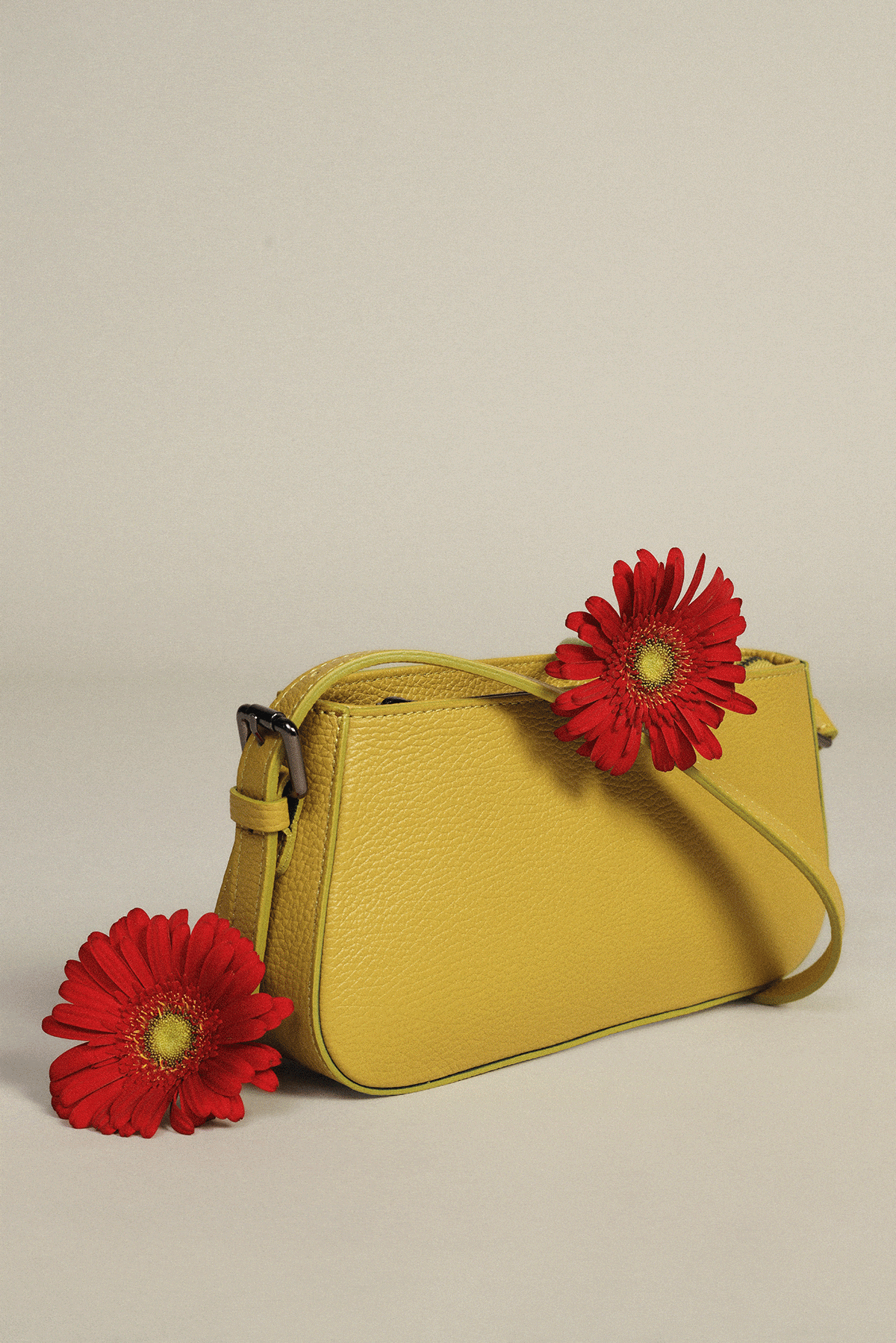 Yellow crossbody bag with red gerbera, stacked brown and black handbags with pale roses, and pale pink studded shoulder bag with yellow flowers