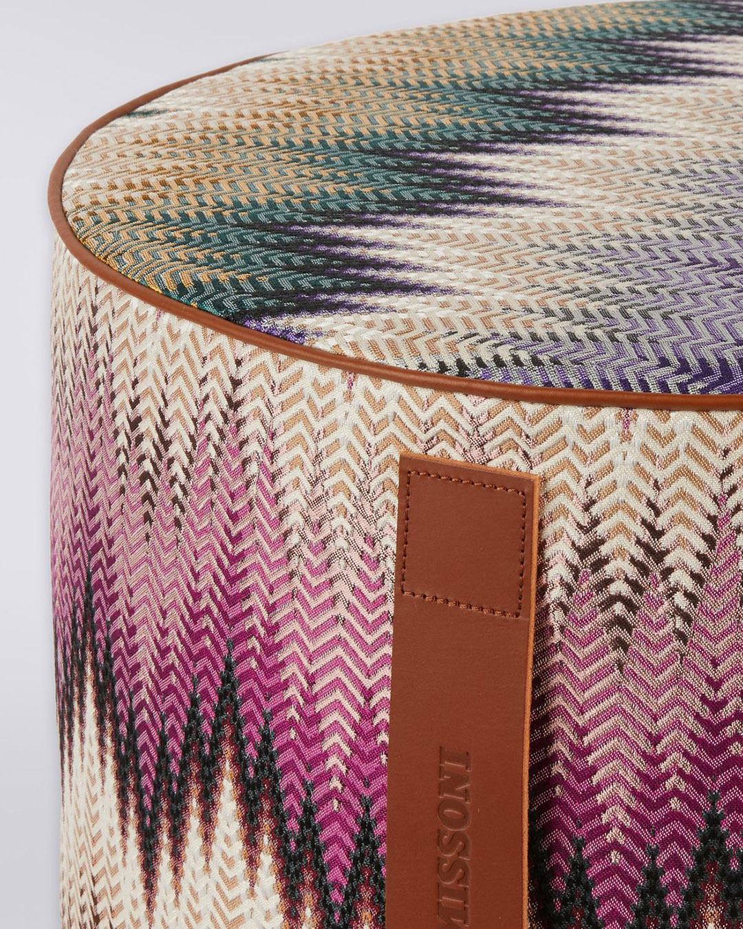 Round designer pouf with chevron woven pattern in pink, purple, green and cream, leather side handle