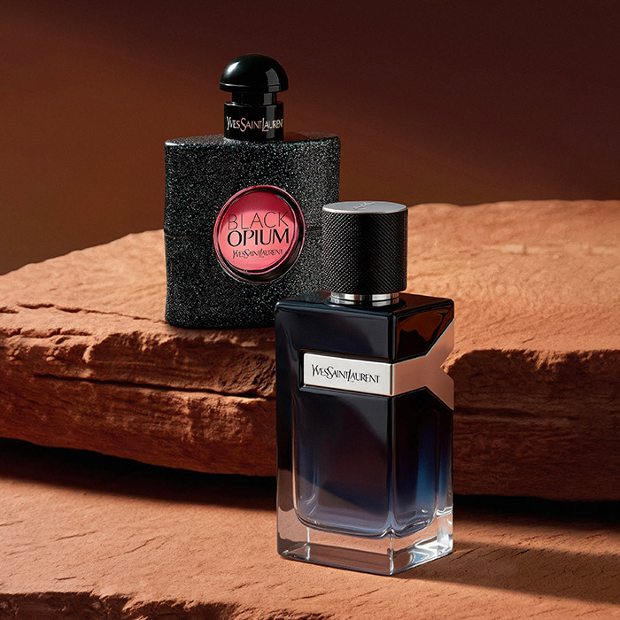 Flaconi di profumo YSL Black Opium e Y su una roccia rossa.