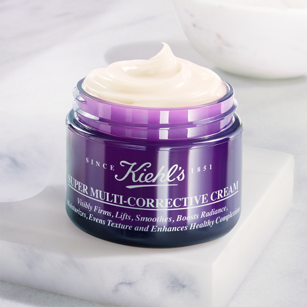 Vasetto aperto della Super Multi-Corrective Cream di Kiehl's con coperchio viola e texture cremosa in primo piano.