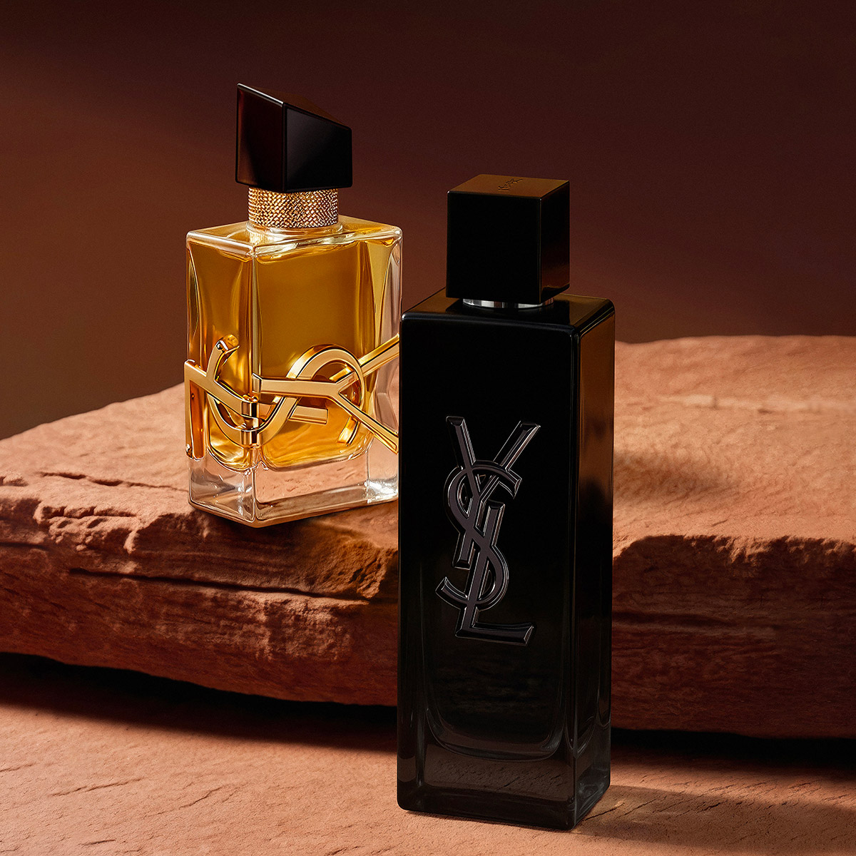 Flaconi di profumo YSL Libre e MYSLF su una roccia rossa.