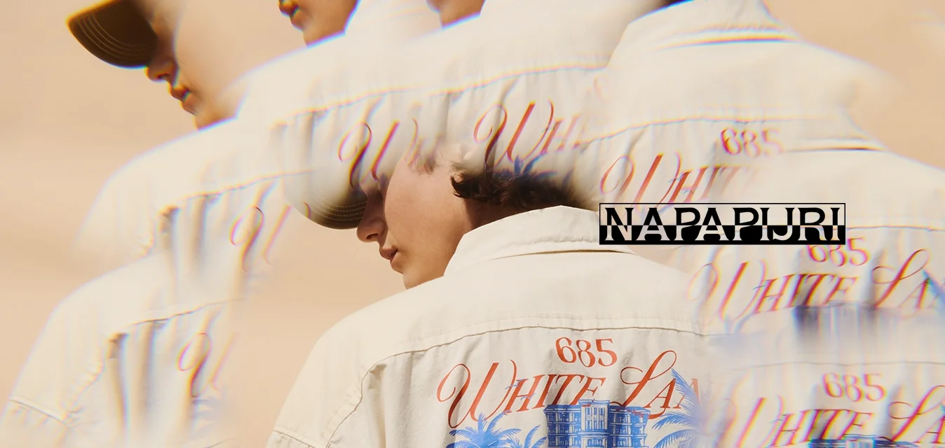 Persona che indossa giacca beige e cappellino, sul retro mostra una grafica blu e rossa di palme e un edificio, con effetto sfocatura a esposizione multipla.