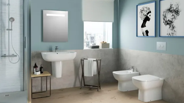 Modern bathroom with pedestal sink and mirror, glass shower, bidet and toilet, towel rail and blue walls with city view