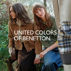 Tre persone vicino al lago, due sedute su una panchina con giacche casual, una in piedi con un cappotto beige che tiene una borsa a quadri.