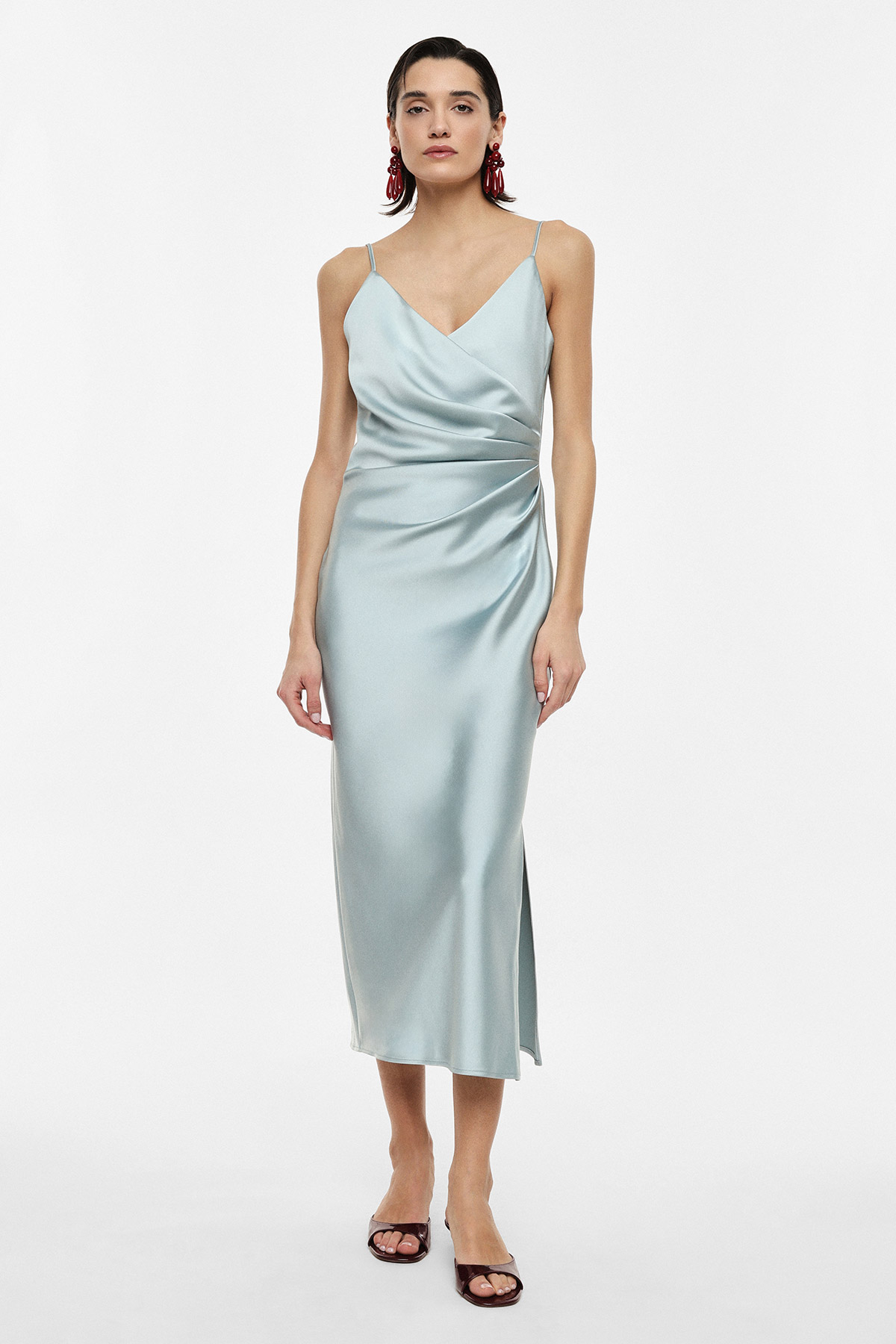 Woman modelling pale blue satin slip midi dress with spaghetti straps, ruched side, V-neck, side slit and black heels