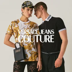 Due persone sono in piedi una accanto all'altra; una indossa una camicia a fantasia, pantaloni in pizzo neri e tiene una borsa nera, l'altra indossa una maglia nera e jeans larghi.