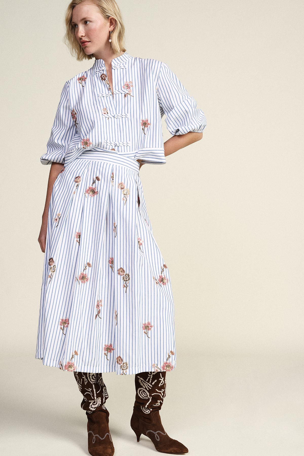 Woman wearing blue-and-white striped blouse and matching floral midi skirt with embroidered brown suede boots
