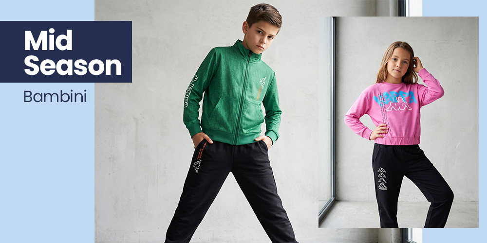 Two children modelling mid-season kids' sportswear: boy in green zip jacket and black joggers; girl in pink sweatshirt and black joggers