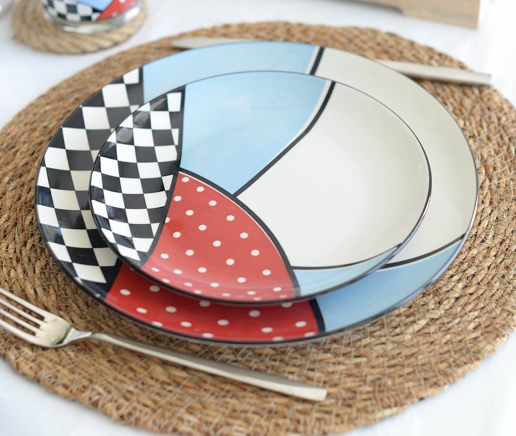 A ceramic cat in a top hat holds a bouquet of spring flowers in a whimsical garden.