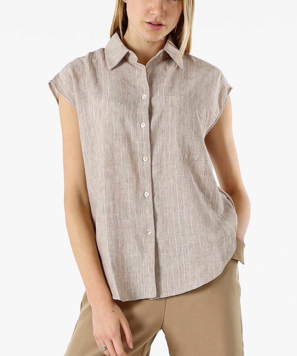 Woman wearing beige short-sleeve linen button-front shirt with chest pocket and khaki trousers on white background