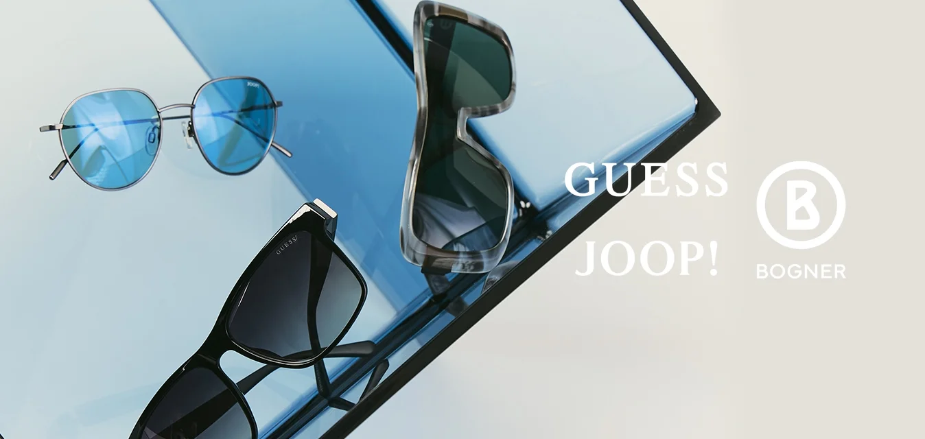 Tre paia di occhiali da sole con stili di montatura diversi e colori delle lenti che riposano su pannelli di vetro blu riflettenti inclinati.