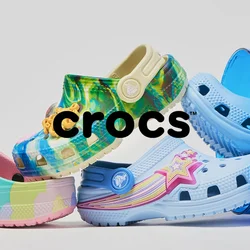 Cinque scarpe Crocs colorate disposte in un gioco di equilibrio, con due all'interno di un secchio traslucido blu ribaltato, su sfondo bianco.