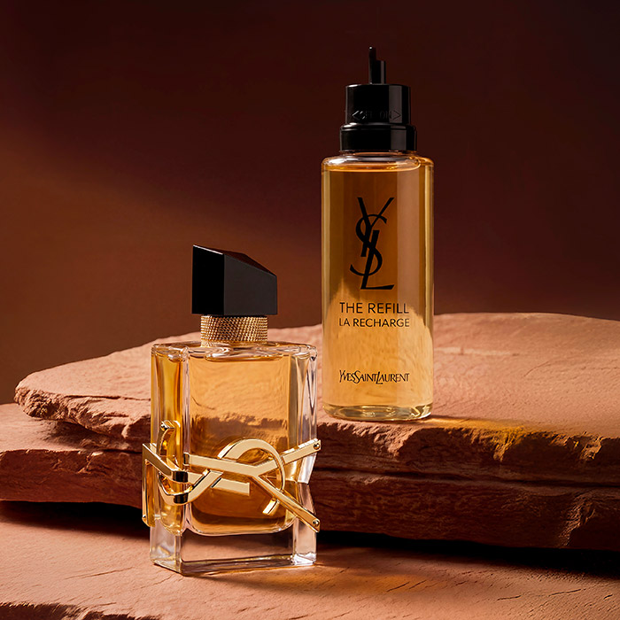 Un flacone di profumo YSL Libre e la sua ricarica su una roccia rossa.