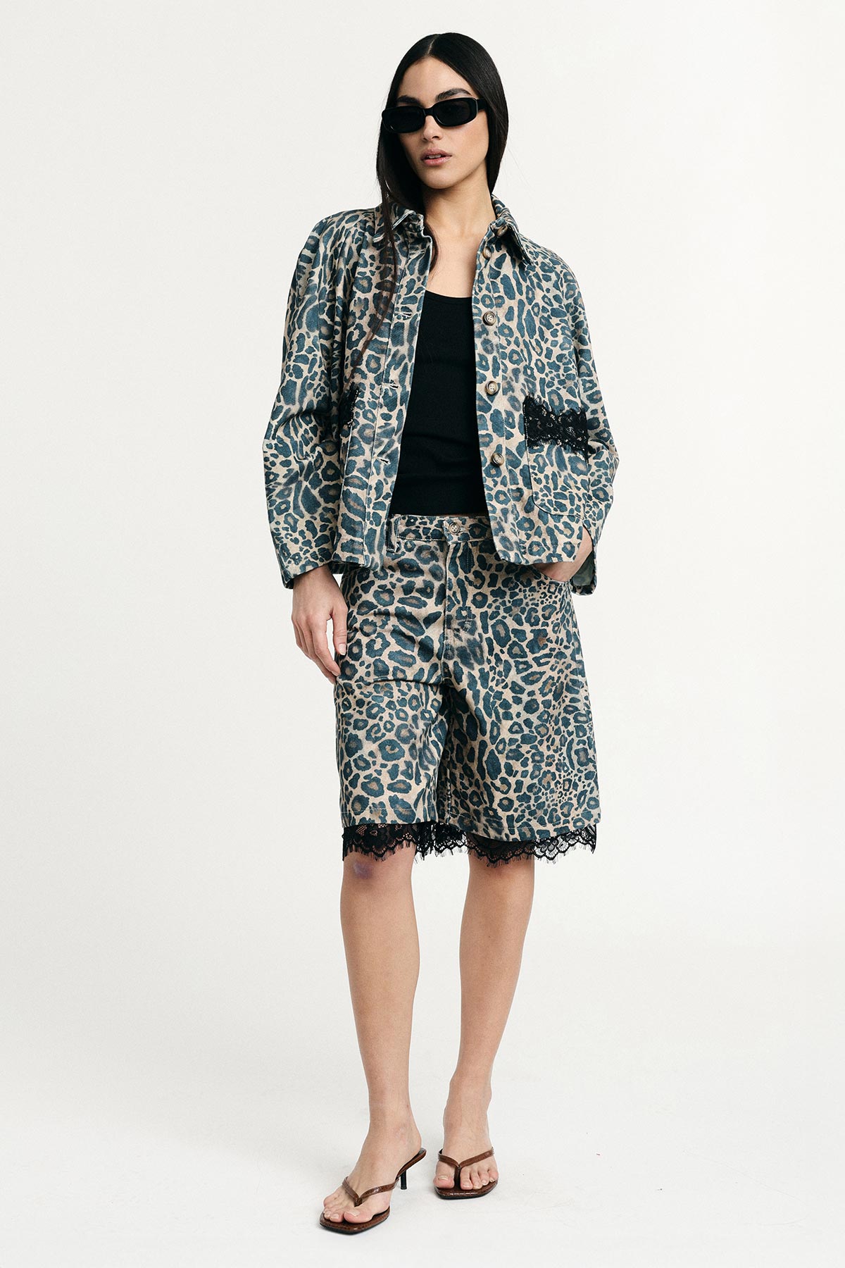 Woman model wearing leopard-print denim jacket and matching lace-trim Bermuda shorts, black tank, sunglasses and sandals
