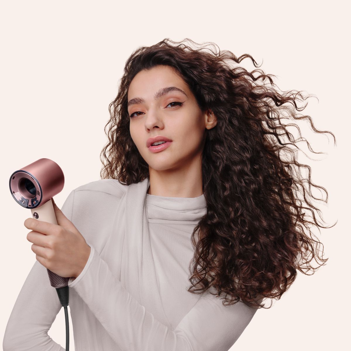 Una modella riccia che utilizza l’asciugacapelli Dyson Supersonic Travel per asciugarsi i capelli.